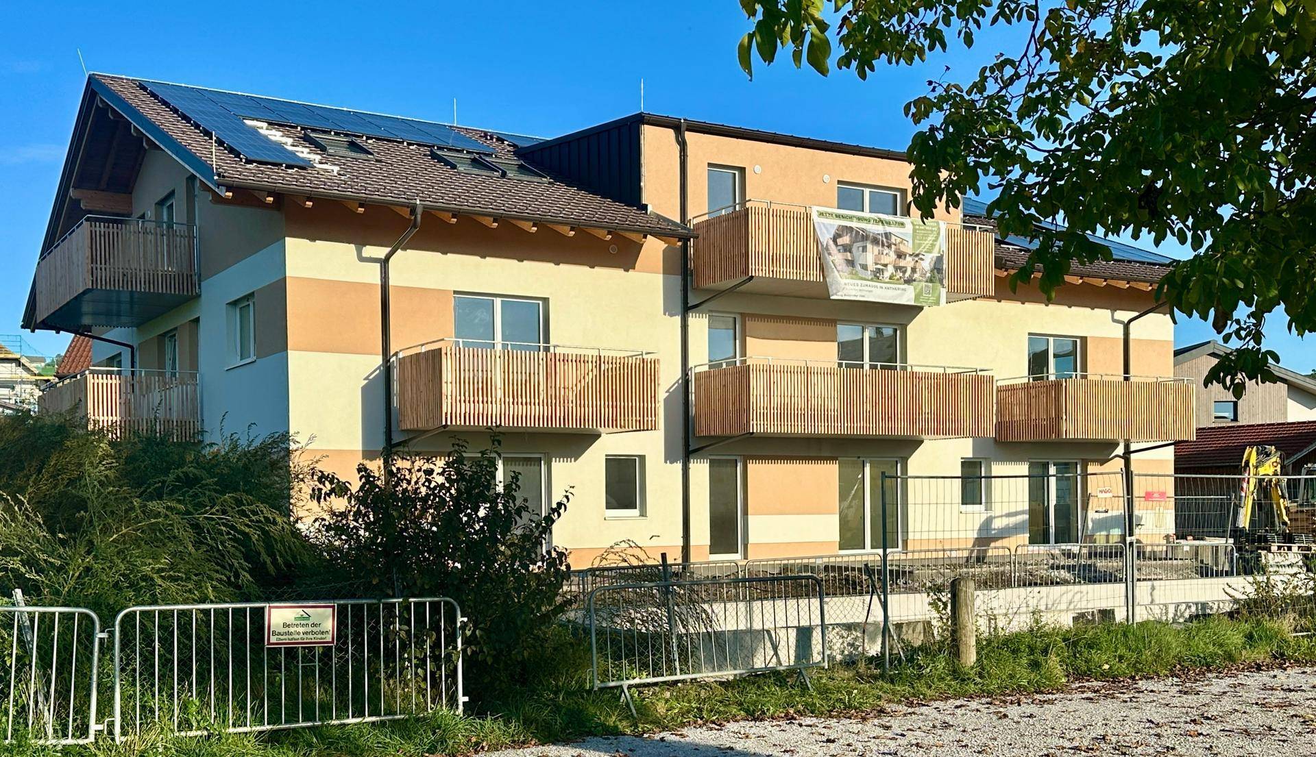 Modernes Mehrfamilienhaus mit Balkonen und Photovoltaikanlage auf dem Dach.