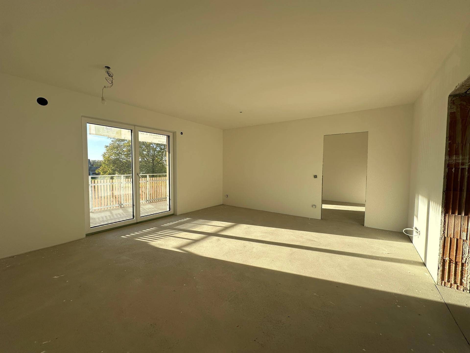 Heller, unmöblierter Wohnbereich mit Zugang zu einem Balkon und viel natürlichem Licht.