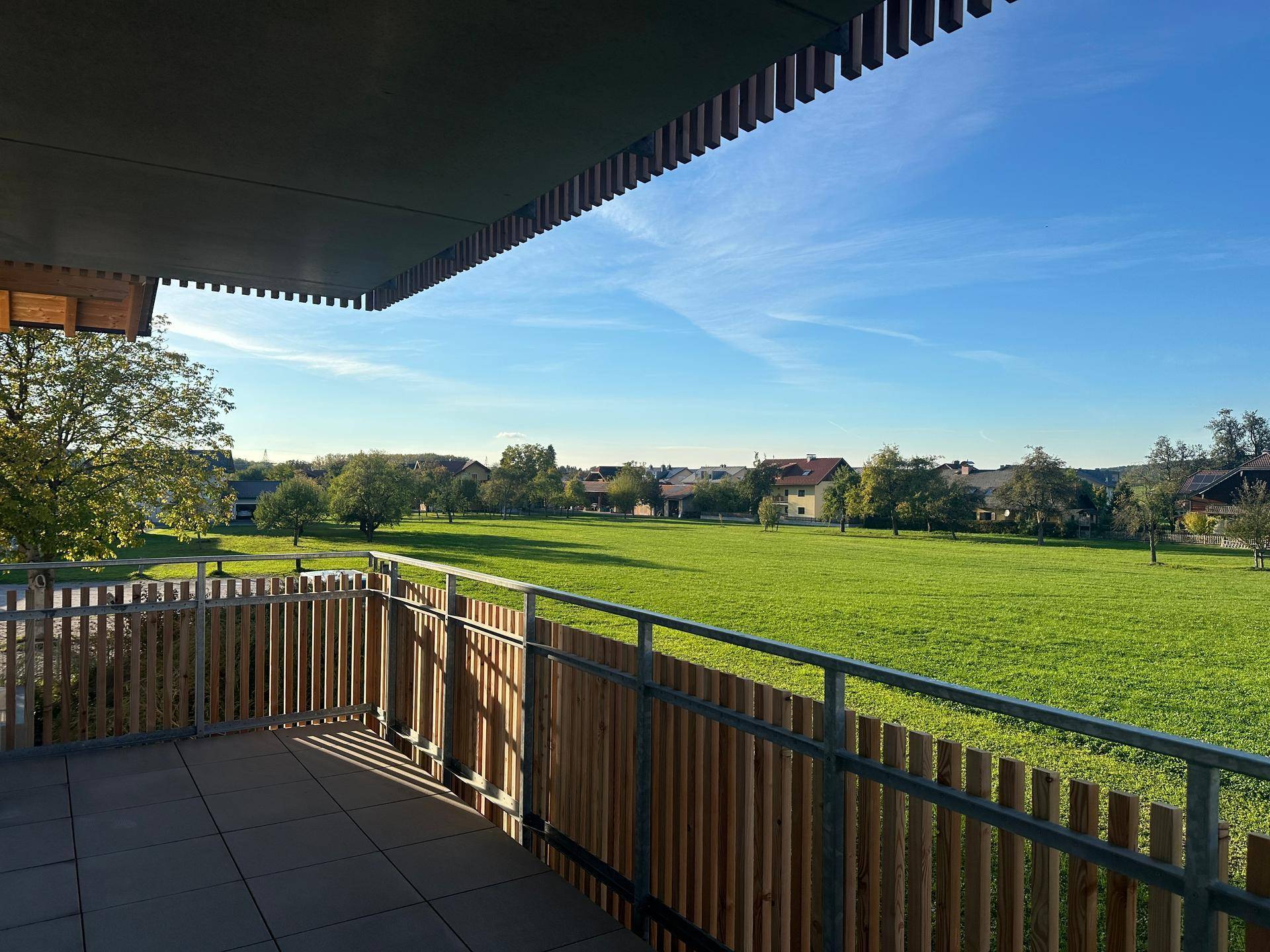 Geräumiger Balkon mit Fliesenboden und unverbautem Blick auf die umliegende Natur und Landschaft.