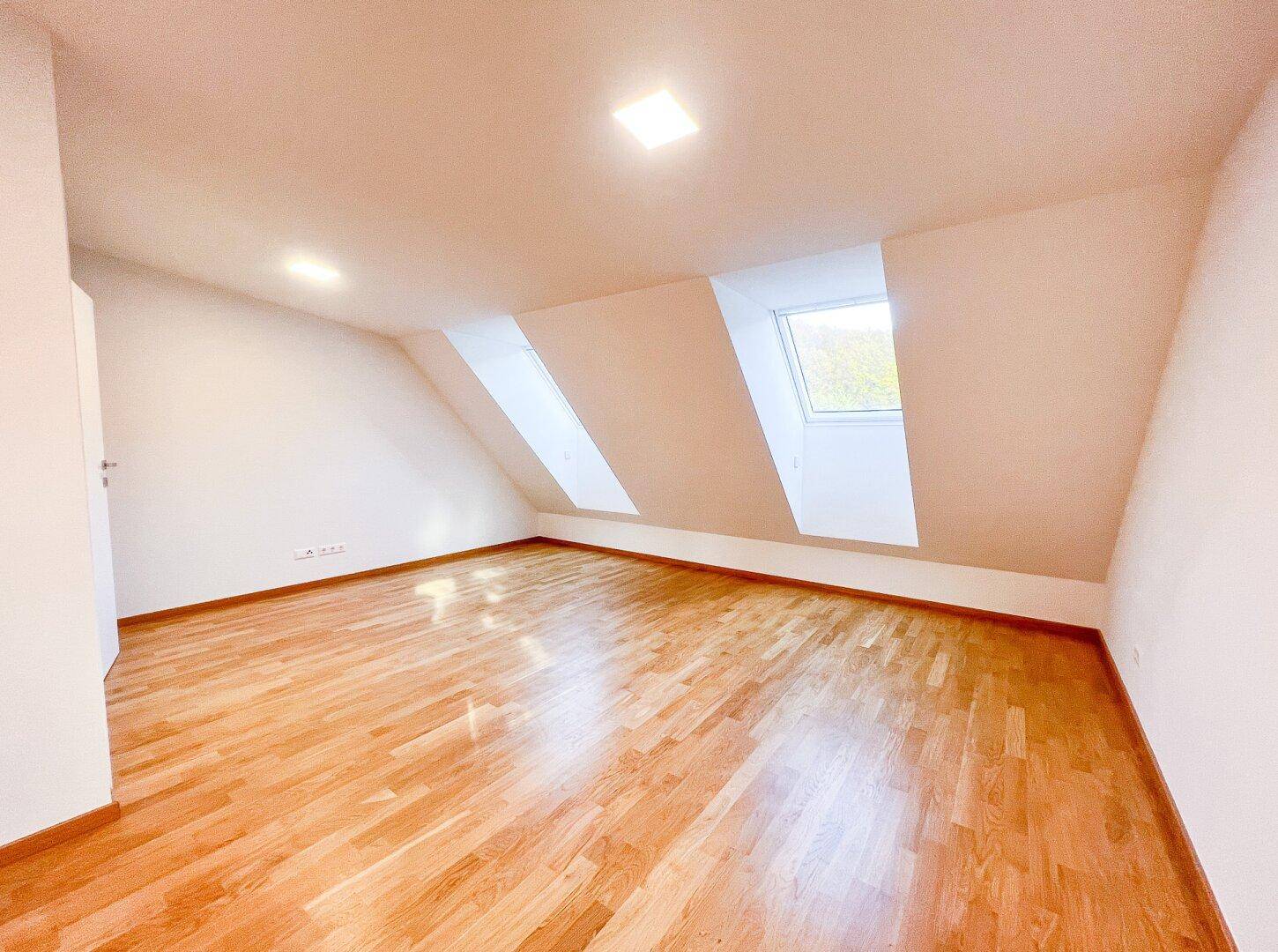 Helles Schlafzimmer mit Parkettboden und Dachschrägen, ideal für ein ruhiges Rückzugsgebiet.