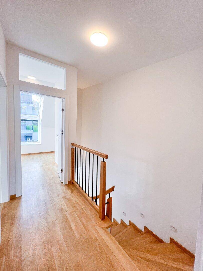 Heller Flur im Obergeschoss mit Holzparkett und Blick in ein weiteres Zimmer.