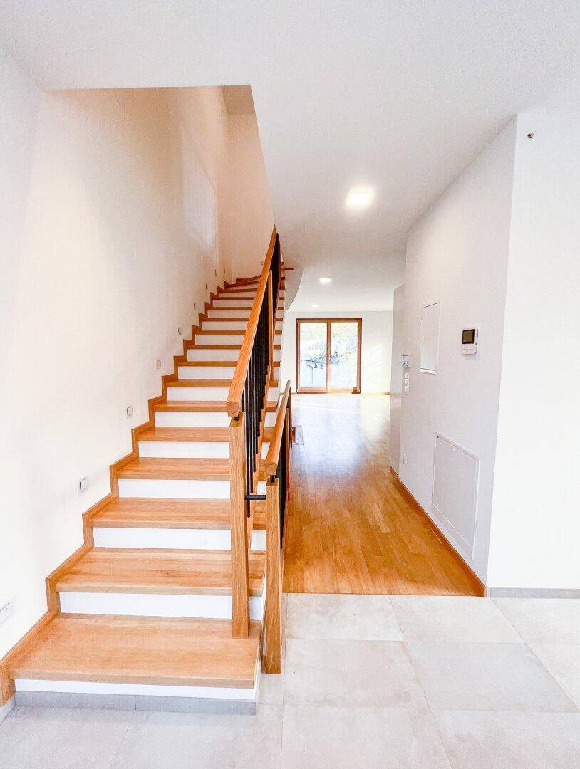 Elegante Holztreppe mit schwarzem Geländer, verbindet die verschiedenen Ebenen des Hauses.