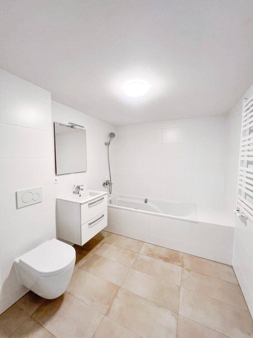 Modernes Badezimmer mit Badewanne, wandhängender Toilette und beheiztem Handtuchhalter.