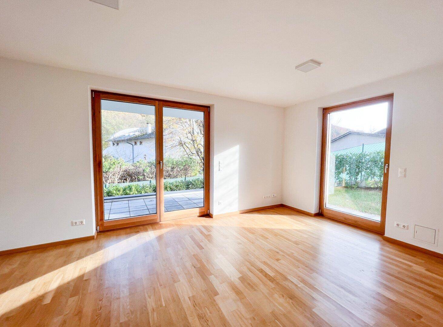 Helles Zimmer mit Parkettboden und großen Schiebetüren zum Garten, bietet direkten Zugang ins Freie.