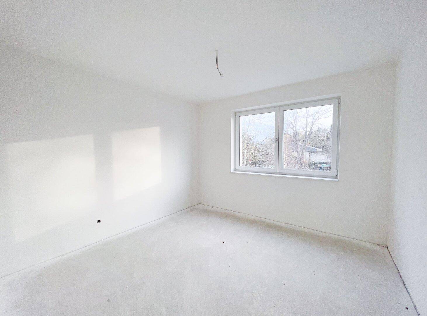 Unmöblierter Raum mit großem Fenster und viel Tageslicht, perfekt für ein Schlafzimmer oder Büro.