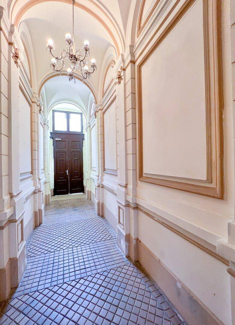 Eleganter Eingangsbereich mit hohen Gewölbedecken, Stuckverzierungen und gemustertem Fliesenboden.