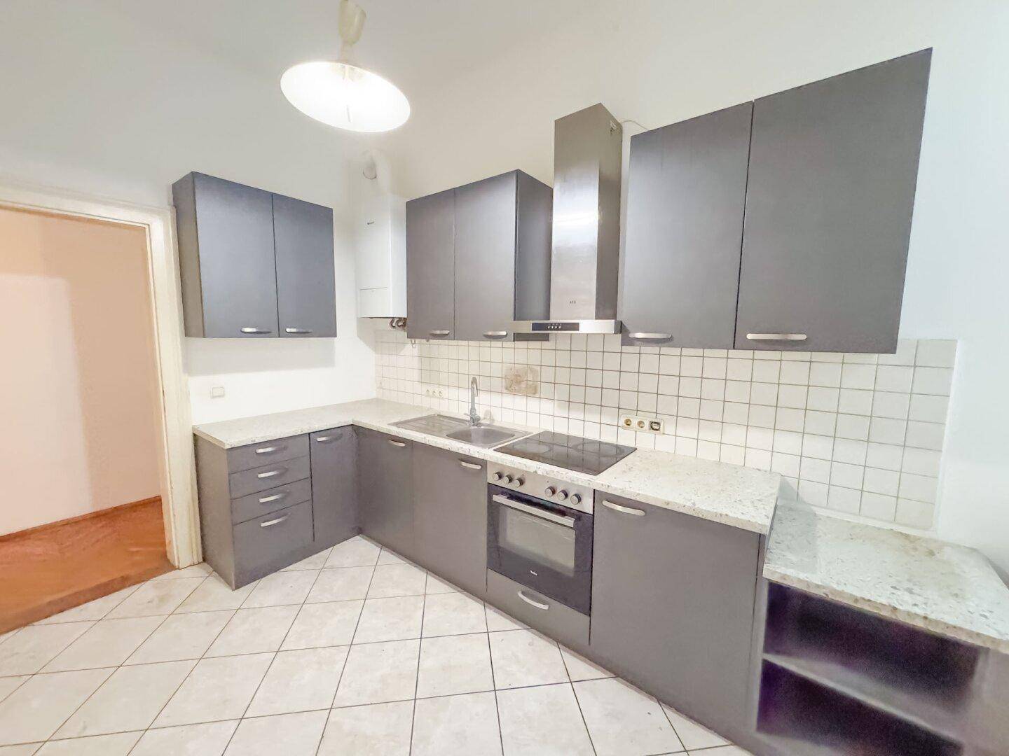 Funktionale Küche mit grauen Schränken, Granitarbeitsplatte und Fliesenboden.