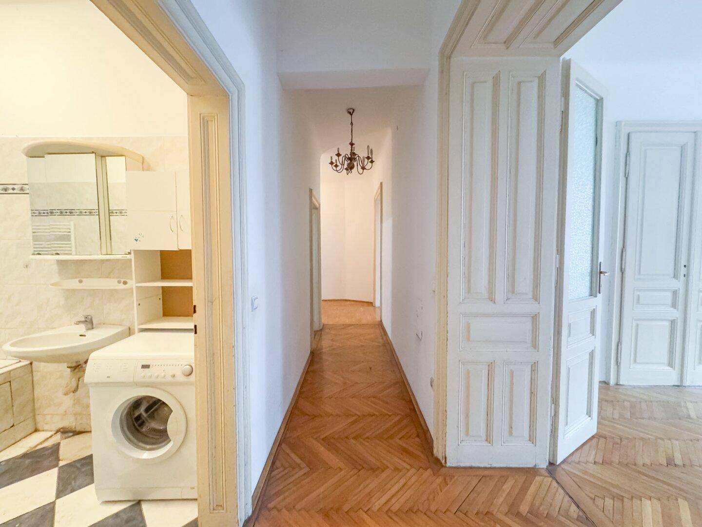 Langer Flur mit Fischgrätparkett, der verschiedene Räume der Wohnung verbindet.