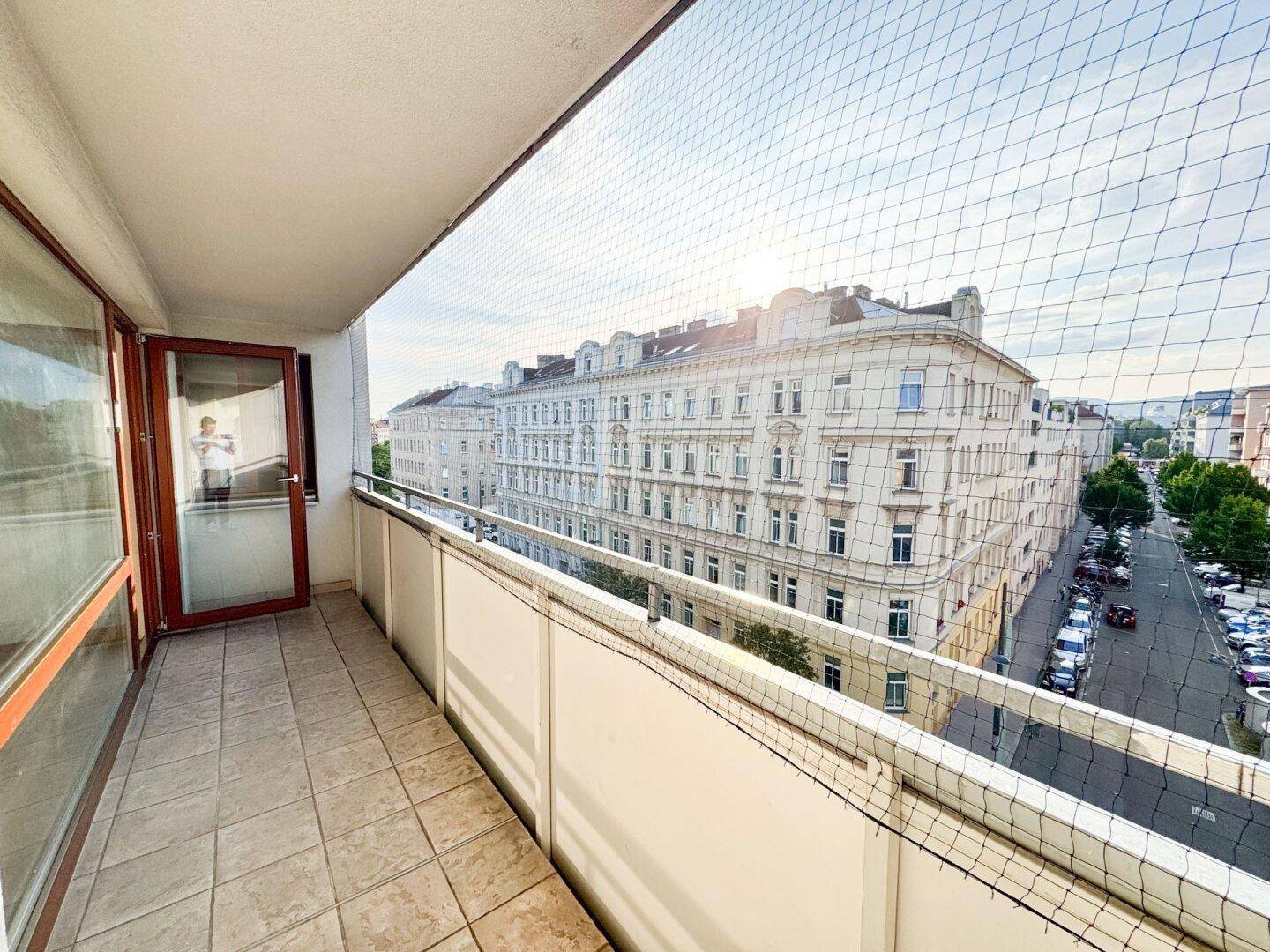 Sonniger Balkon mit Stadtblick und Schutznetz, ideal für entspannte Stunden im Freien.