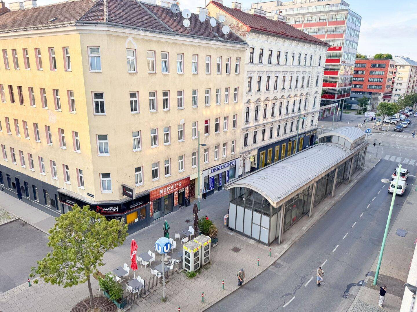 Blick von oben auf die belebte Straße mit Gebäuden und einer Bushaltestelle.