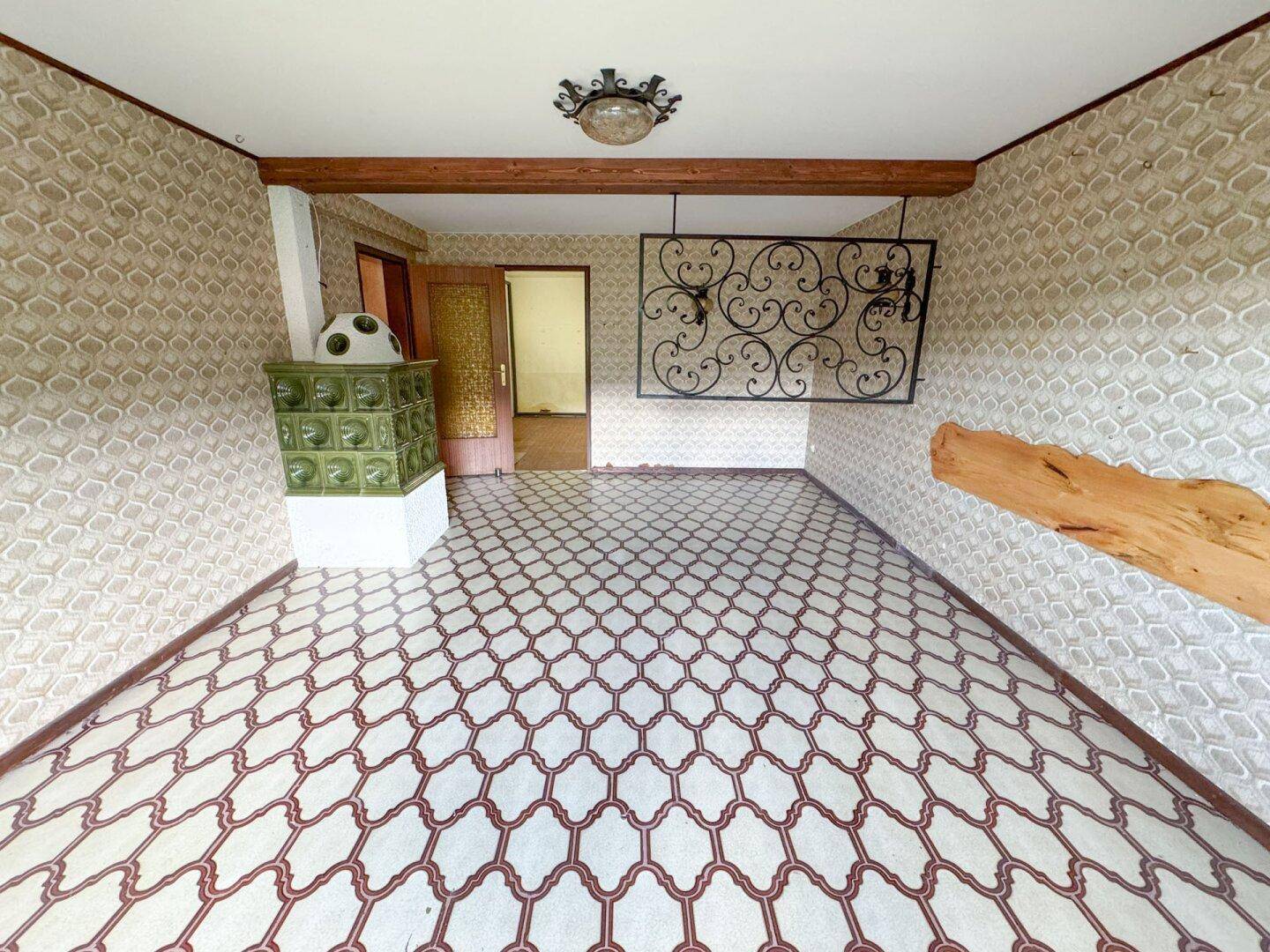 Wohnzimmer mit traditionellem Kachelofen und gemustertem Fliesenboden, rustikaler Charme.