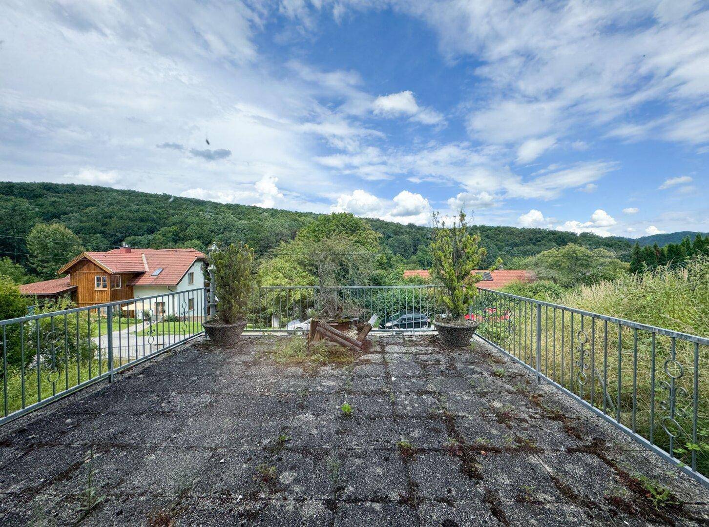 Große, ungenutzte Terrasse mit Metallgeländer und weitem Blick über die Landschaft.