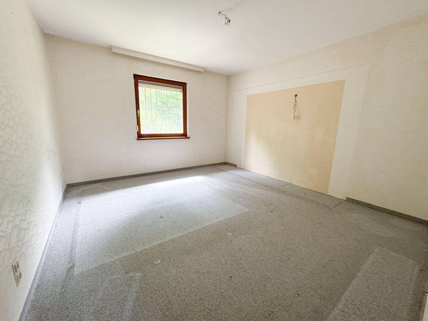 Helles Zimmer mit Teppichboden und Fenster, bietet Potenzial für eine moderne Einrichtung.