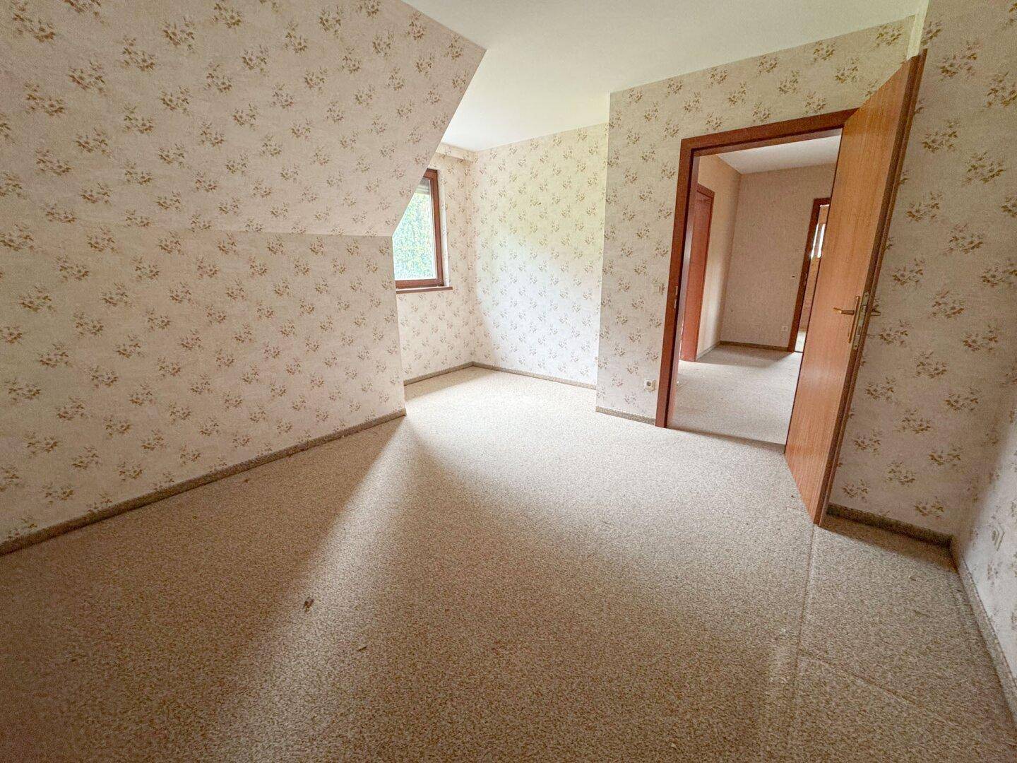 Schlafzimmer mit gemusterter Tapete und Teppichboden, bietet eine gemütliche Atmosphäre.
