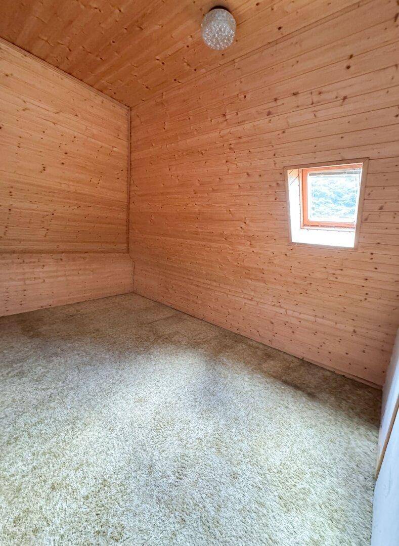 Kleiner Raum mit Holzvertäfelung und Teppichboden, ideal als Abstellraum oder Hobbyzimmer.