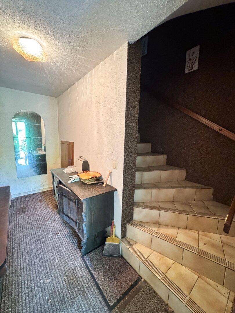 Eingangsbereich mit gefliester Treppe und Teppichboden, führt in die oberen Etagen.