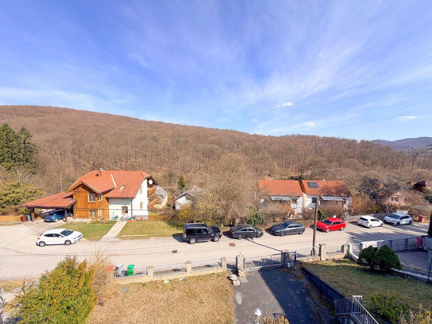 Panoramablick auf die umliegende Wohnsiedlung und bewaldete Hügel unter blauem Himmel.