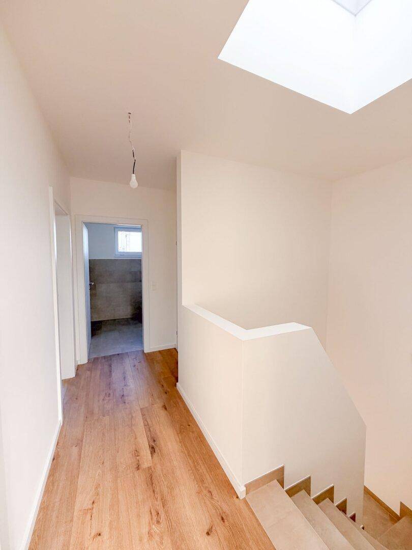 Heller Flur mit Holzboden, Treppe und einem Oberlicht, das viel Tageslicht spendet.