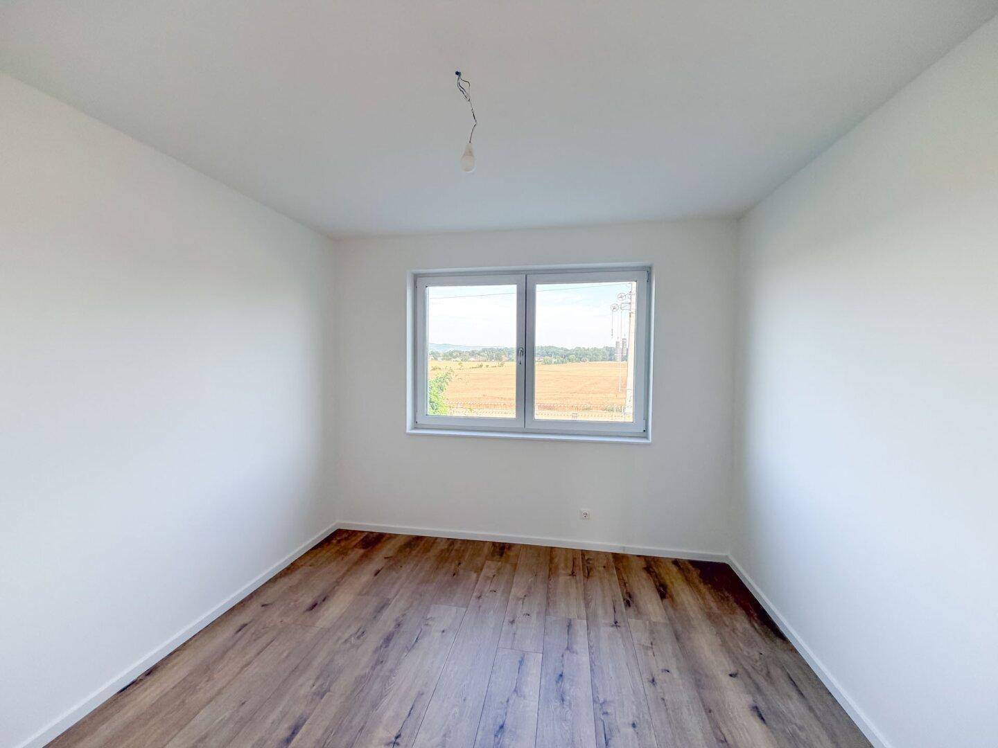 Helles Schlafzimmer mit Holzboden und weitem Blick über die Landschaft.