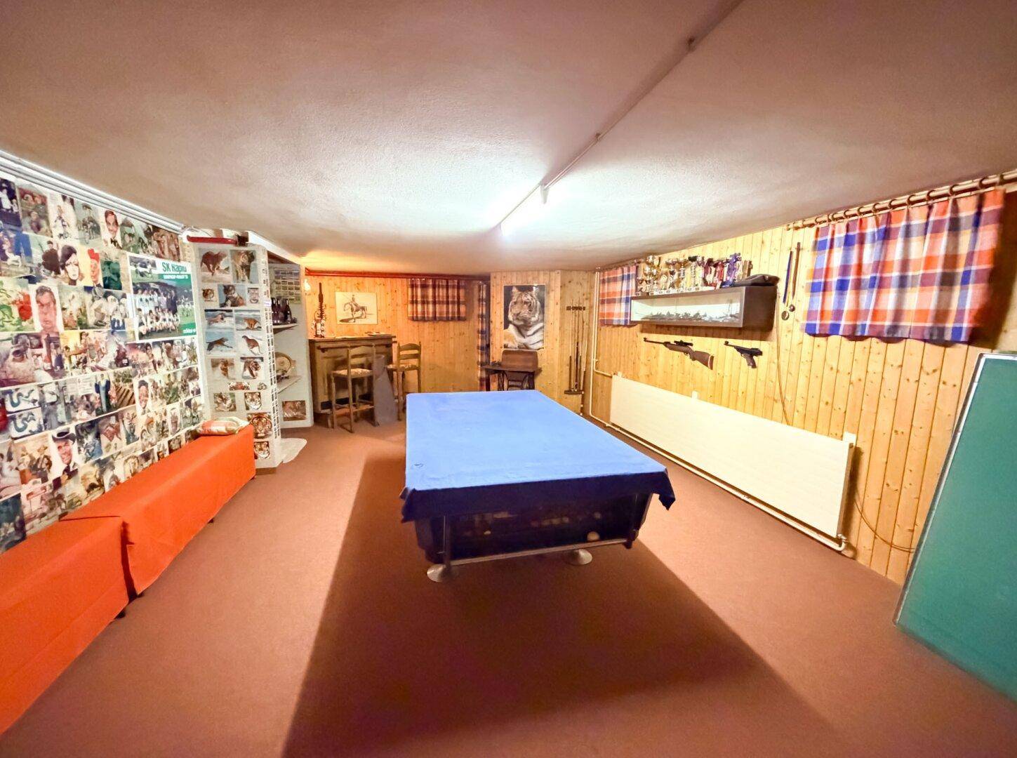 Kellerraum, eingerichtet als Spielzimmer mit Billardtisch, Holzverkleidung und verschiedenen Dekorationen.