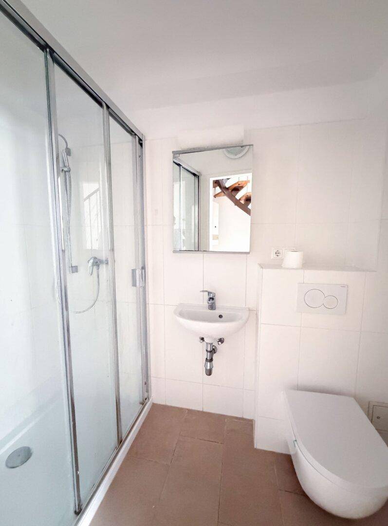 Modernes Badezimmer mit Duschkabine, wandhängendem WC und Waschbecken mit Spiegelschrank.