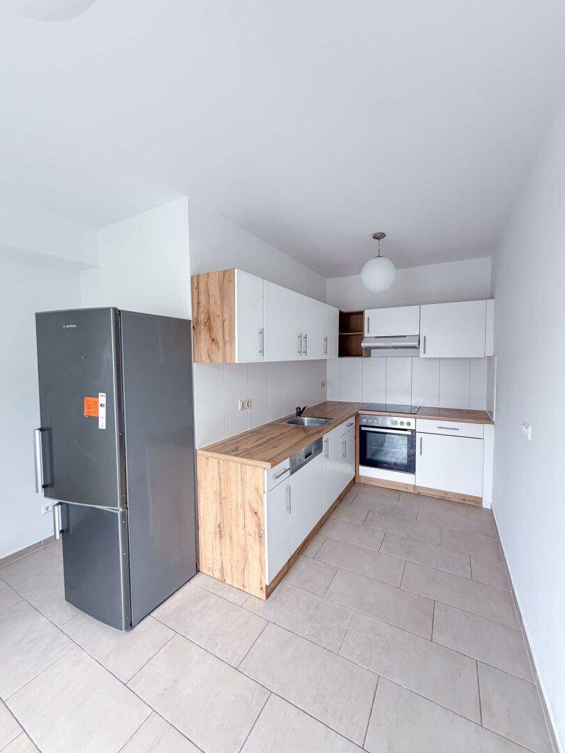 Moderne Einbauküche mit weißen Schränken, Holzoptik-Arbeitsplatten und Fliesenboden.