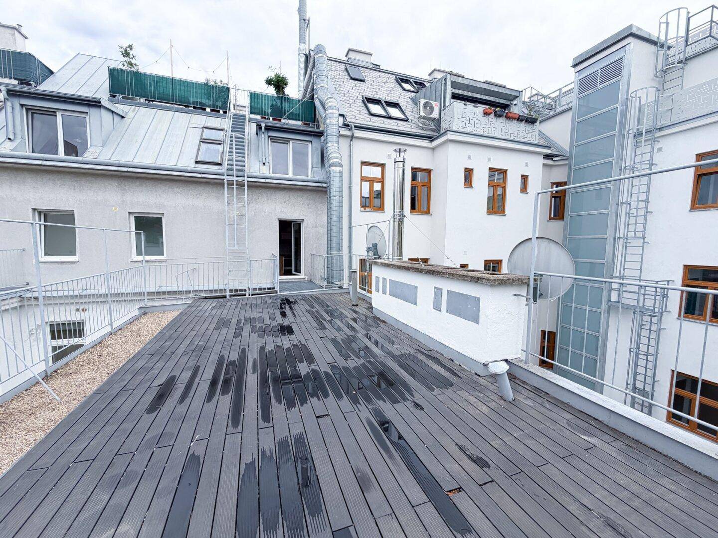 Weitläufige Dachterrasse mit Blick auf die umliegenden Dächer und die Fassade des Gebäudes.