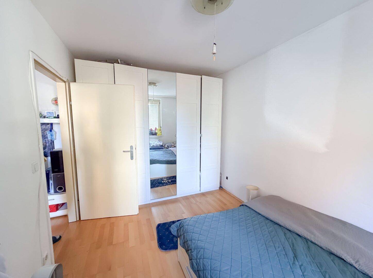 Schlafzimmer mit Bett und großem Spiegelschrank, der den Raum optisch erweitert.