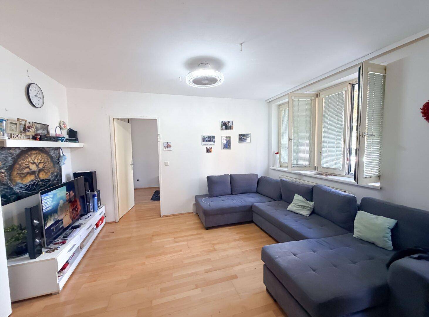 Gemütliches Wohnzimmer mit großem Ecksofa, Fernseher und hellem Holzboden.