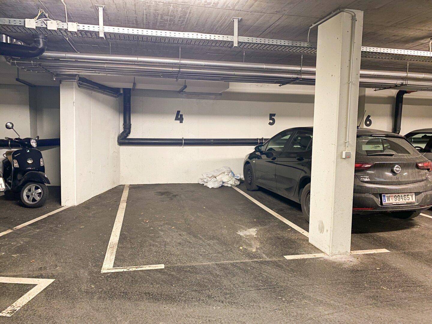 Tiefgarage mit Stellplätzen für Fahrzeuge, inklusive Auto und Roller.