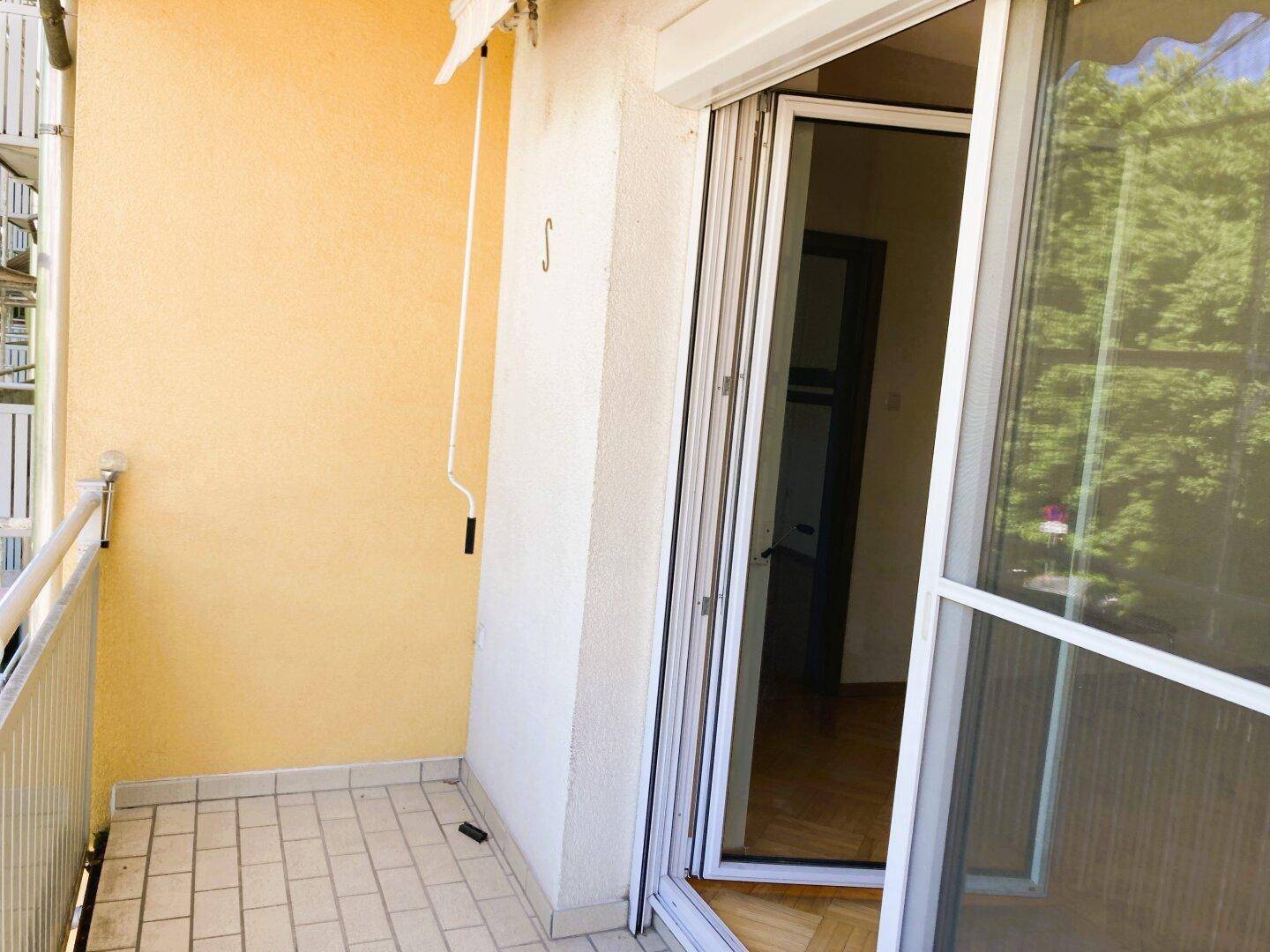 Heller Balkon mit Fliesenboden und weißem Geländer, ideal für entspannte Stunden im Freien.