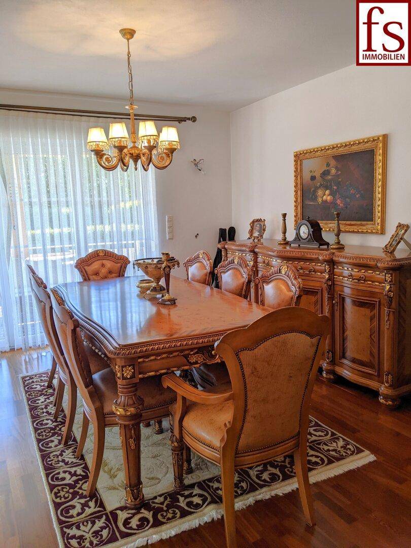 Detailansicht des Esszimmers mit reich verzierten Holzmöbeln und einem opulenten Kronleuchter.