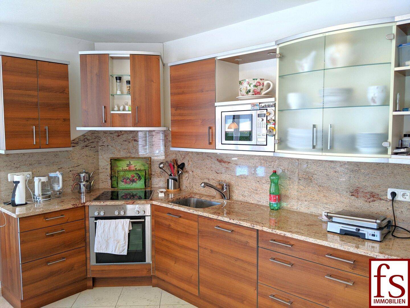 Funktionale Küche mit Holzfronten, Granitarbeitsplatten und integrierten Geräten.