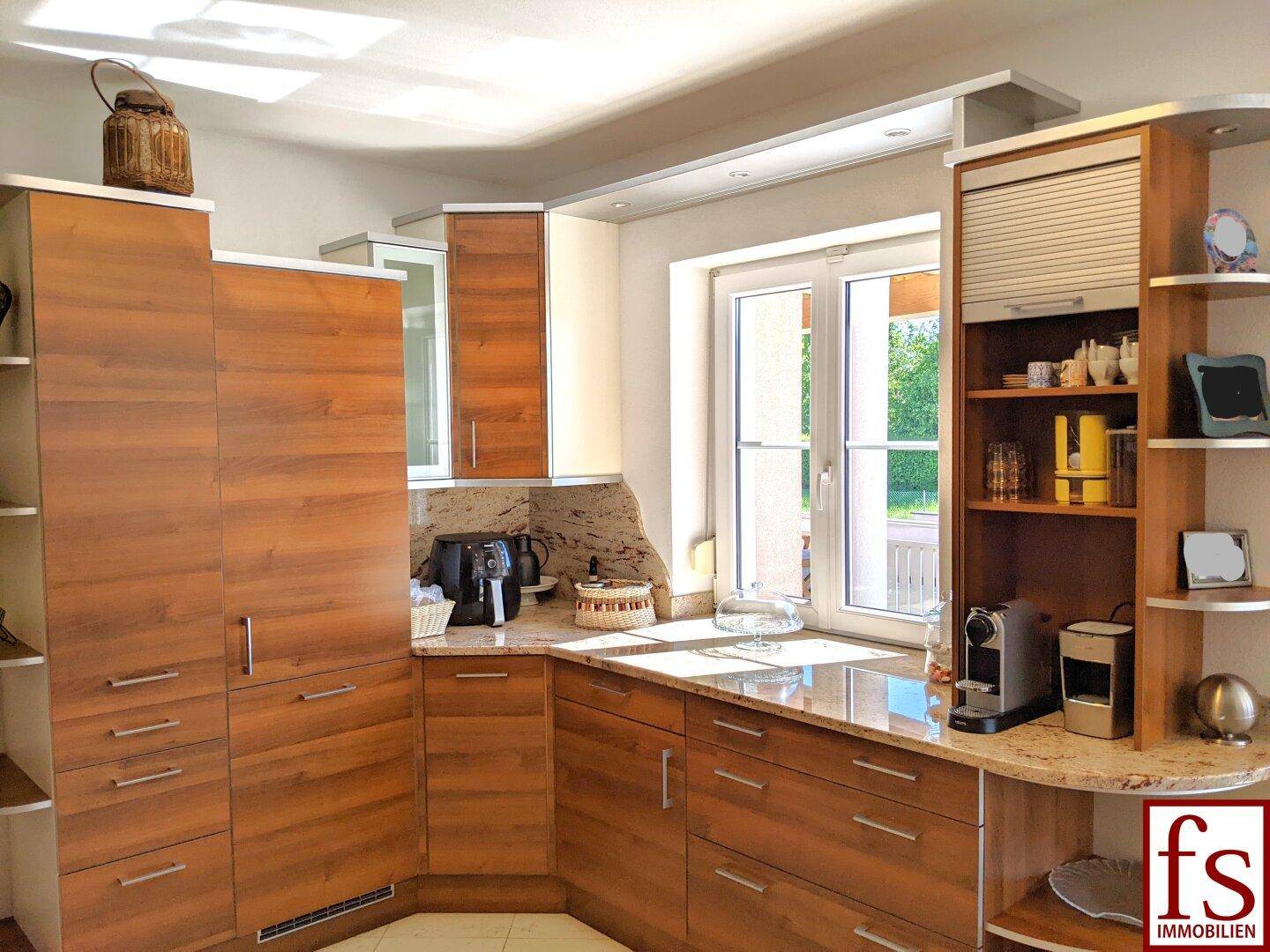 Geräumige Küche mit Holzschränken, Granitarbeitsplatten und einem Fenster mit Blick ins Grüne.
