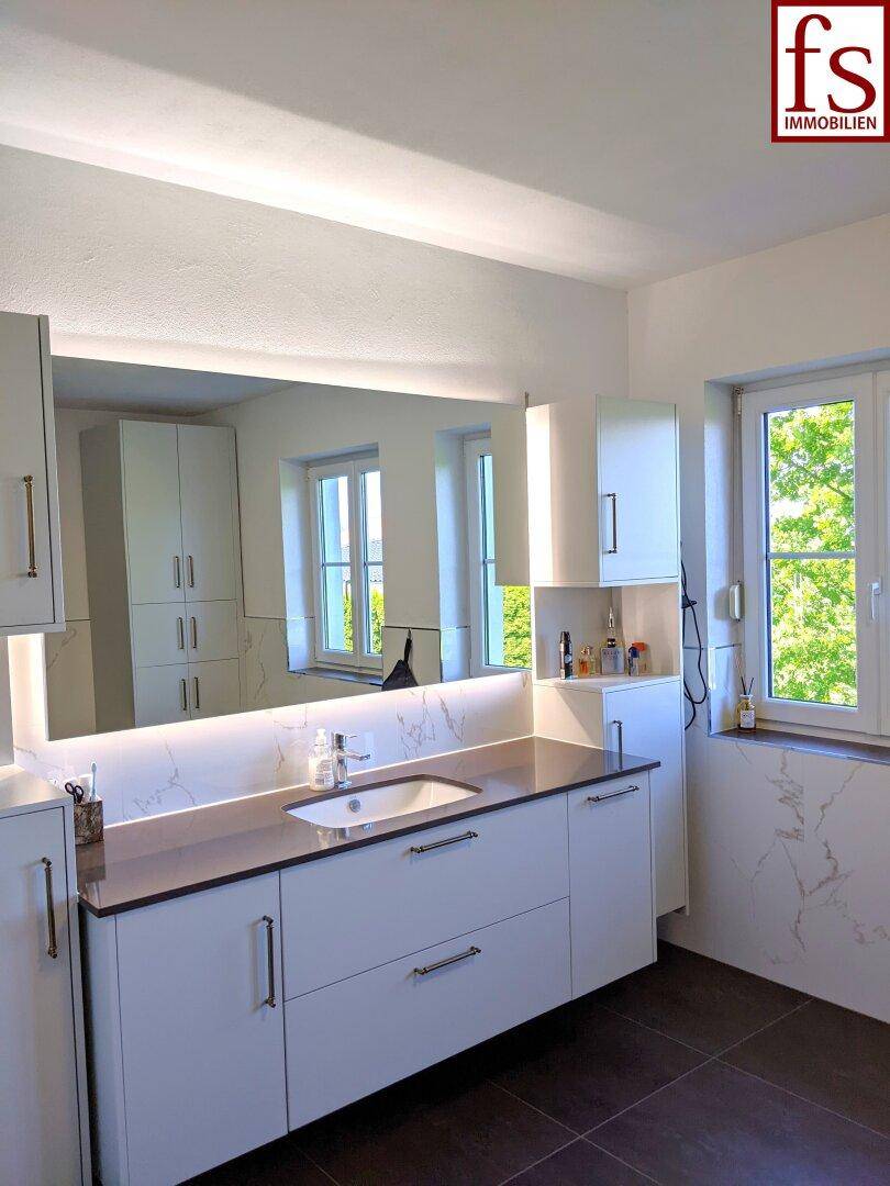 Modernes Badezimmer mit großem Spiegel, Einzelwaschbecken und Fenster für natürliche Belüftung.