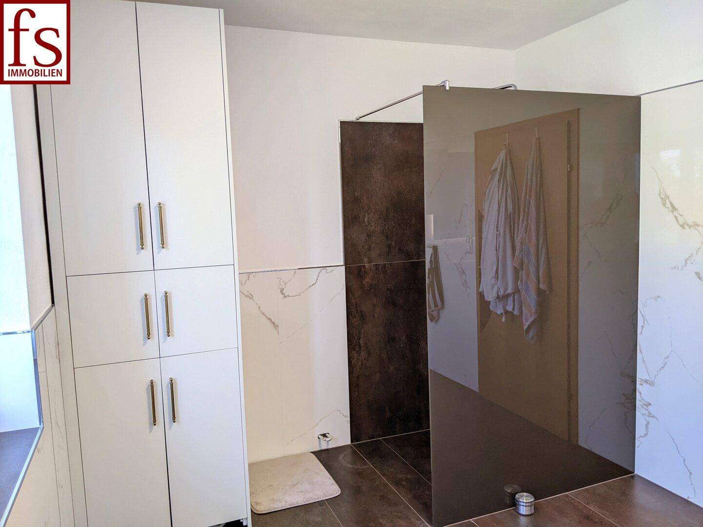 Modernes Badezimmer mit begehbarer Dusche und eleganten Fliesen in verschiedenen Brauntönen.
