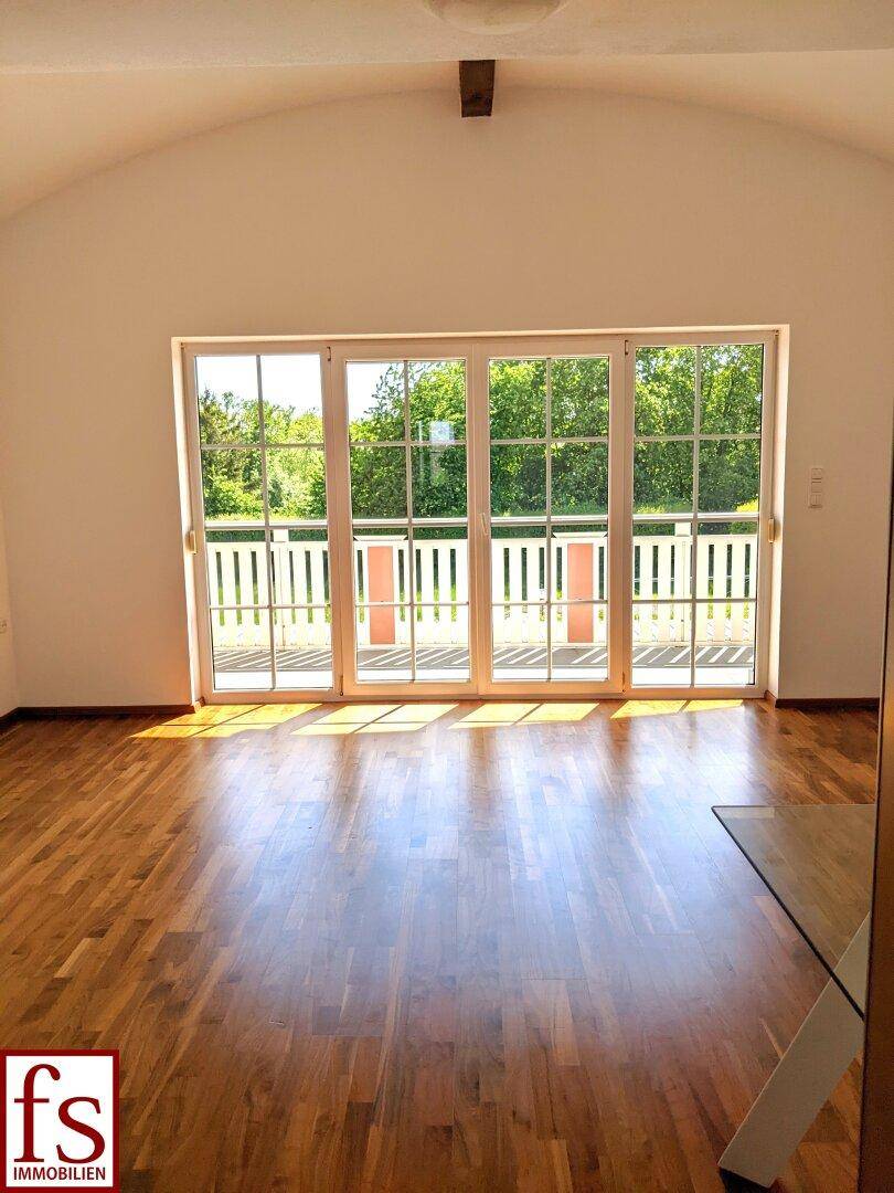 Heller Raum mit Holzboden und großzügigem Zugang zu einem Balkon, ideal für viel Tageslicht.