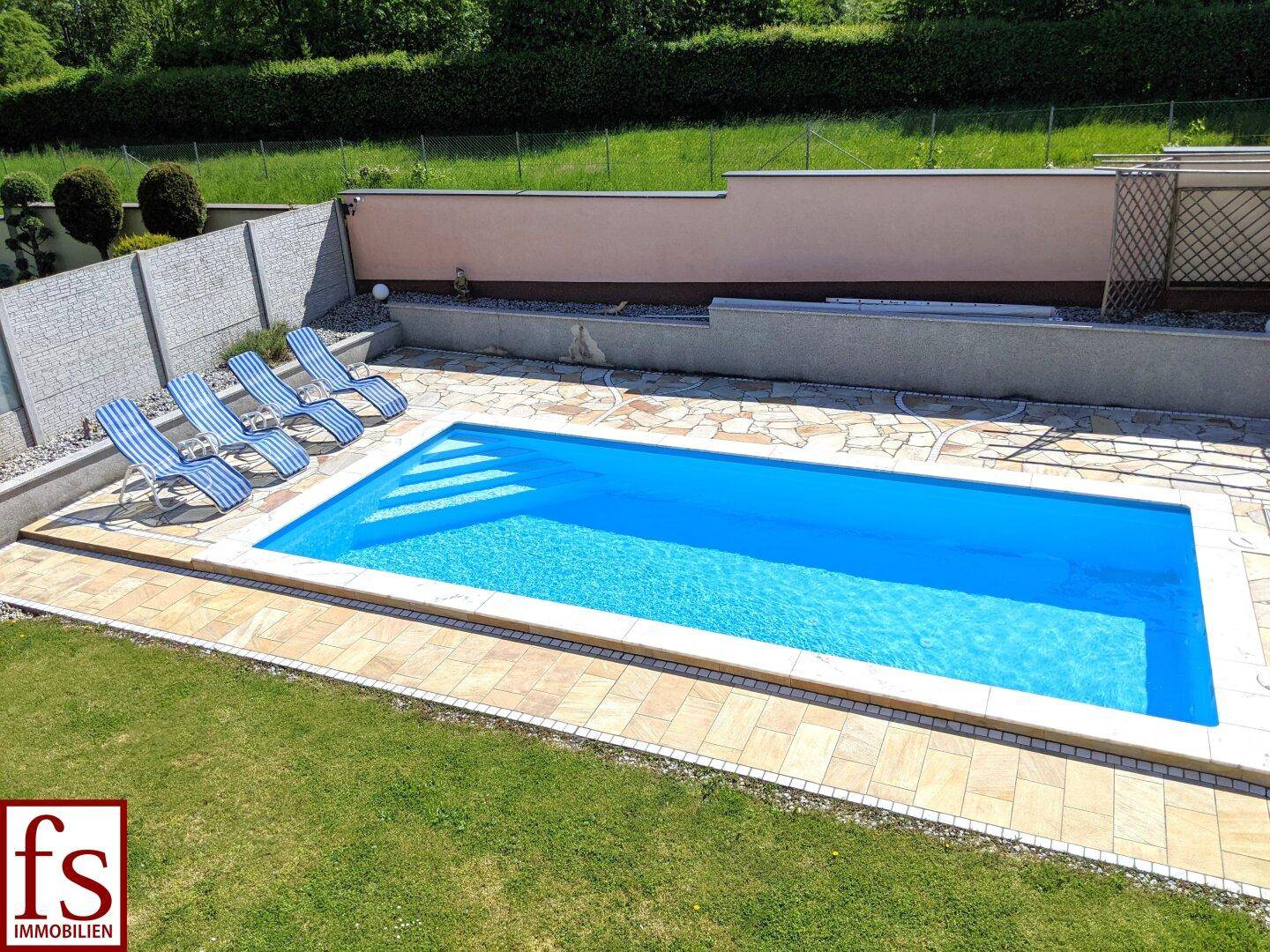 Gepflegter Gartenbereich mit rechteckigem Pool und Liegestühlen für entspannte Sommertage.