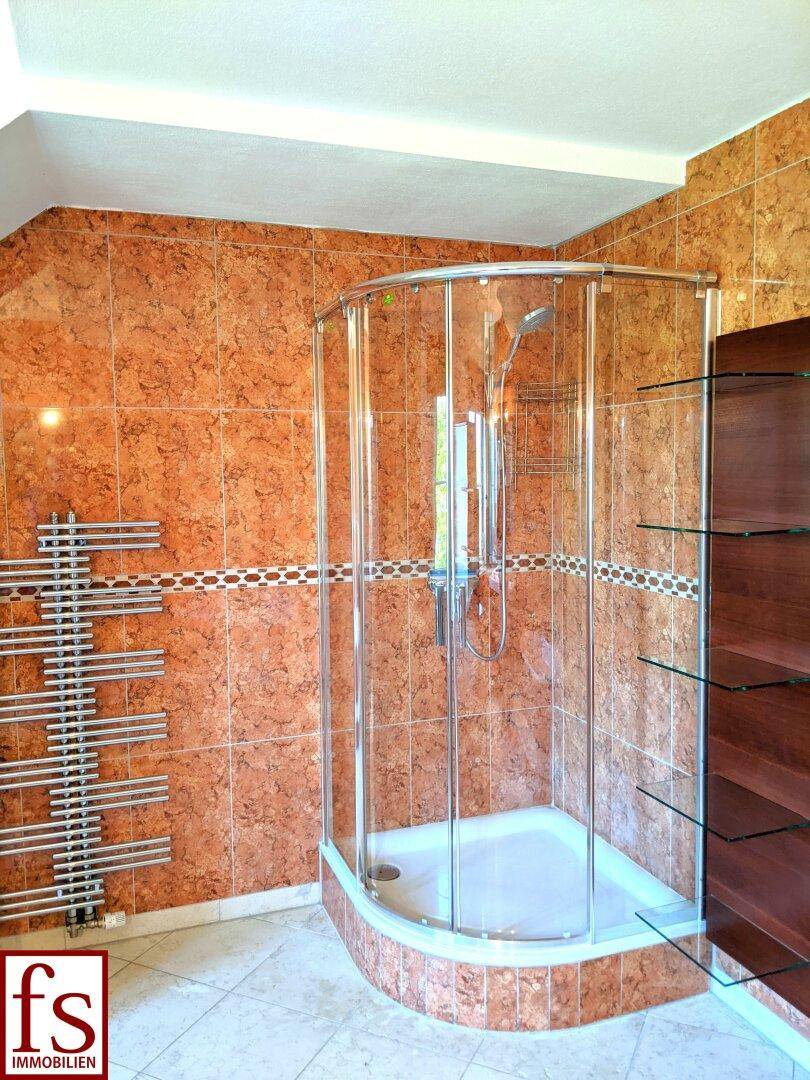 Badezimmer mit Duschkabine, beheiztem Handtuchhalter und gemusterten Fliesen.
