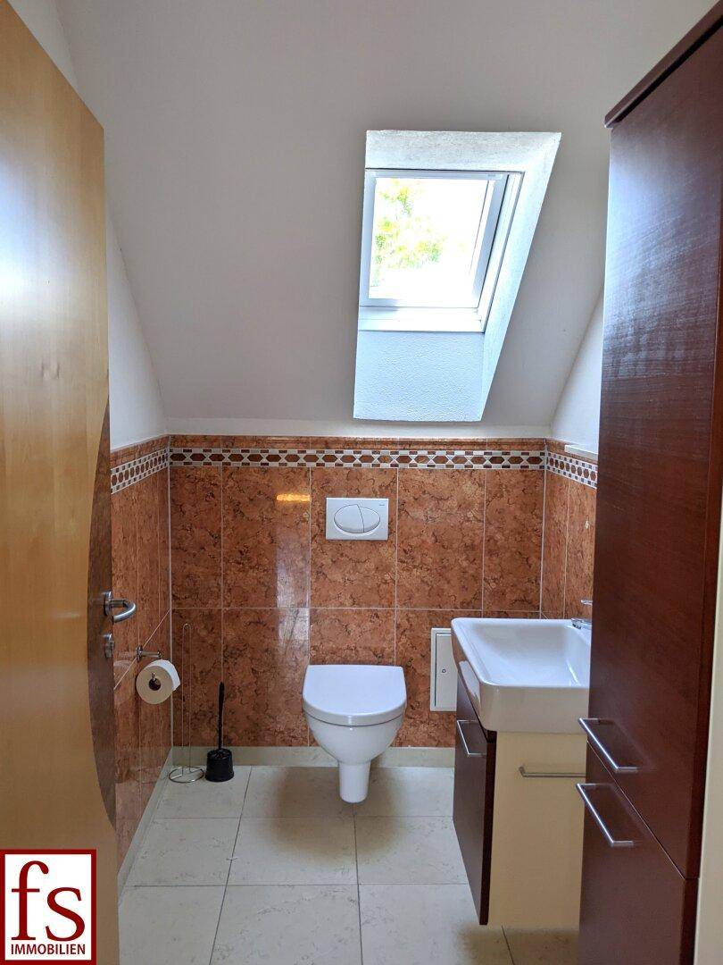 Gäste-WC im Dachgeschoss mit Dachfenster, Wand-WC und kleinem Waschbecken.