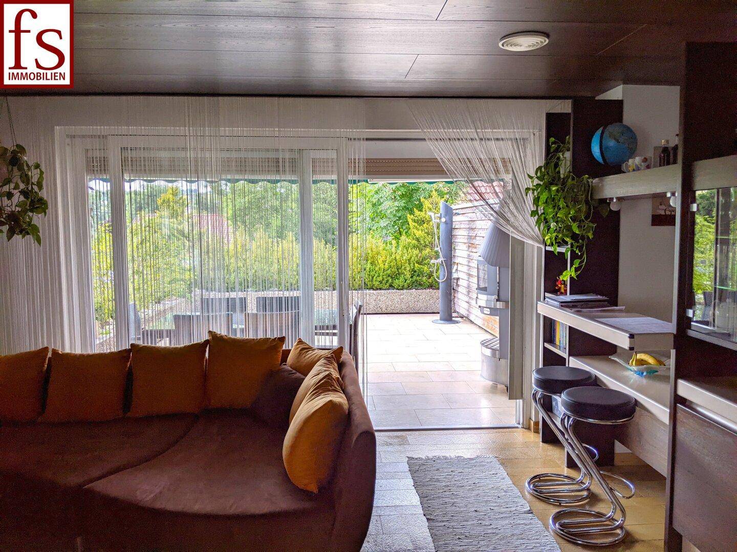 Helles Wohnzimmer mit Sofa und direktem Zugang zu einer großzügigen Terrasse.