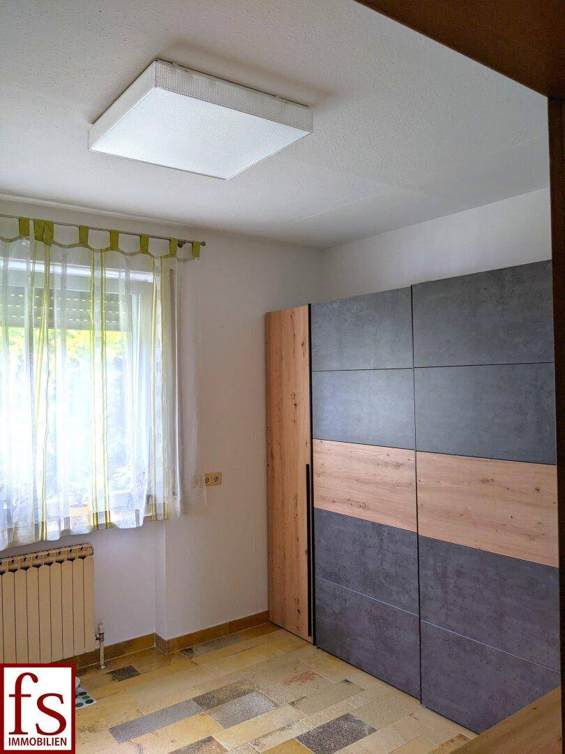 Schlafzimmer mit modernem Kleiderschrank, Fenster und Heizkörper.