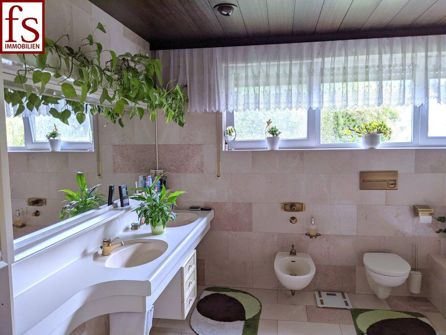 Geräumiges Badezimmer mit Doppelwaschbecken, Bidet und Fenster.