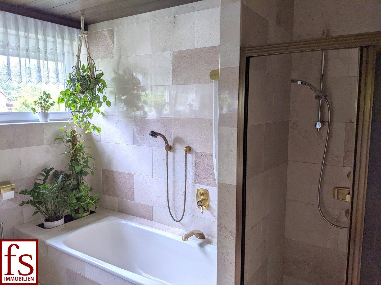 Badezimmer mit Badewanne, Duschkabine und hellen Fliesen.