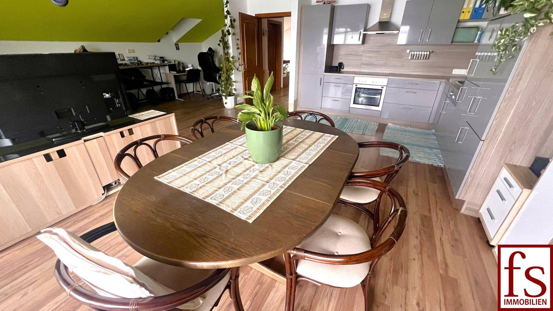 Essbereich mit Holztisch und Stühlen, angrenzend an die moderne Küche.
