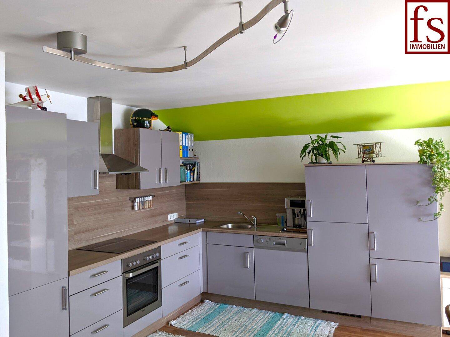 Moderne Einbauküche mit grauen Fronten, Holz-Arbeitsplatte und Dachschräge.