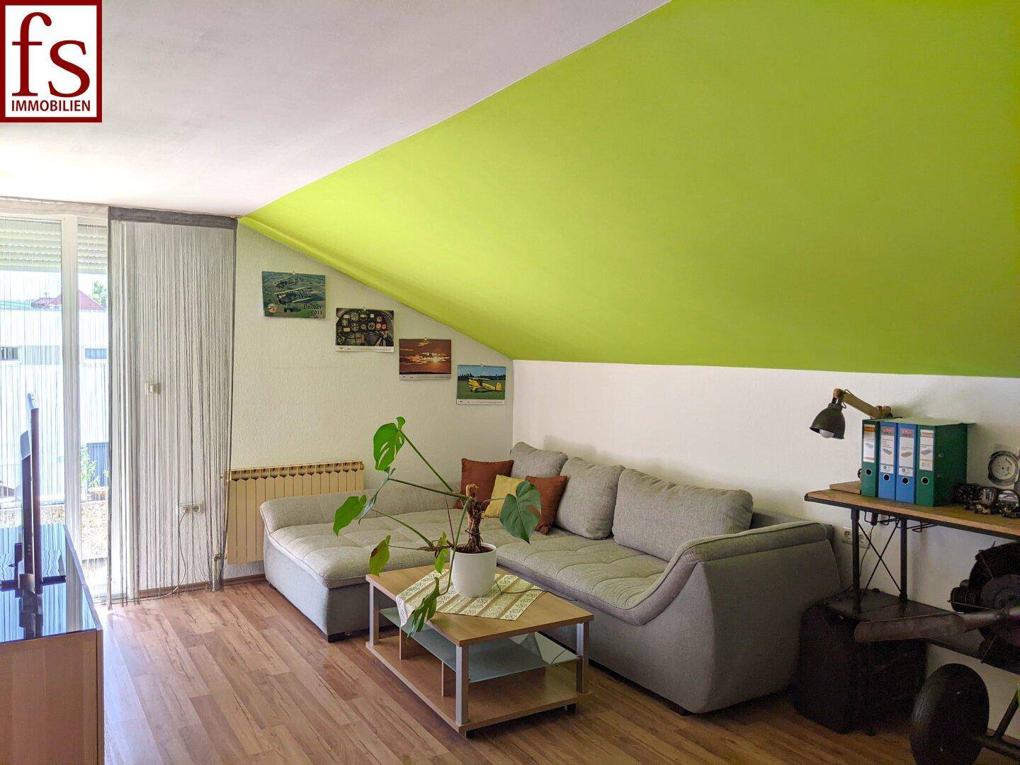 Gemütlicher Wohnbereich mit Sofa, Couchtisch und charakteristischer Dachschräge.