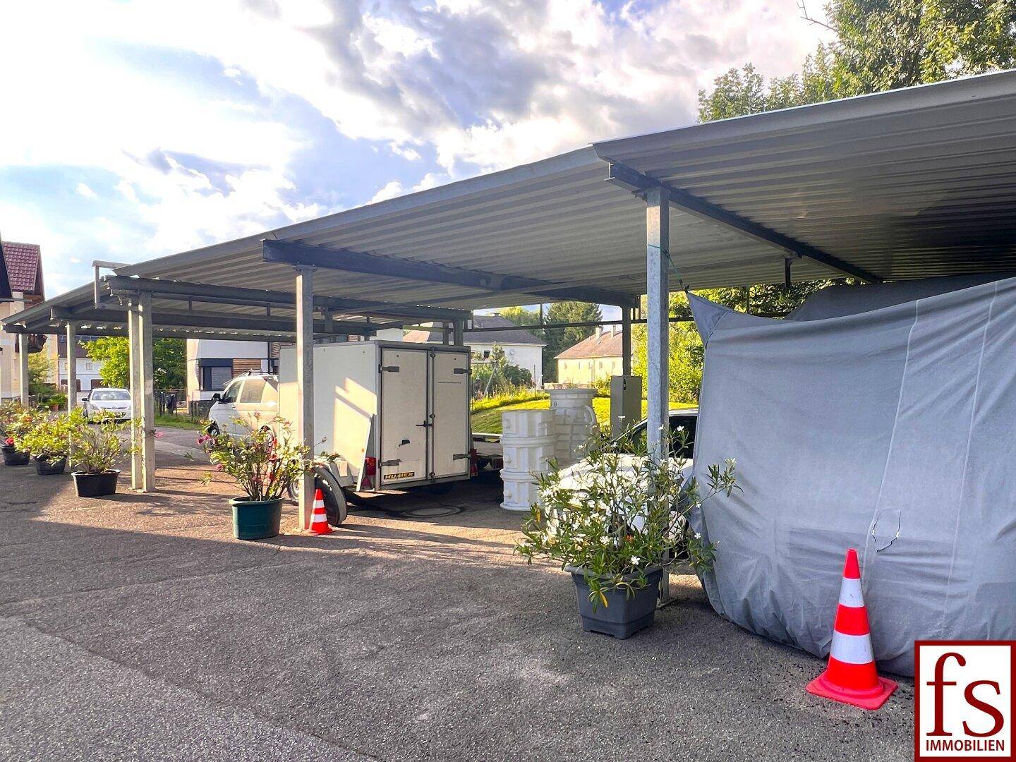 Geräumiger Carport mit mehreren Stellplätzen und Topfpflanzen.