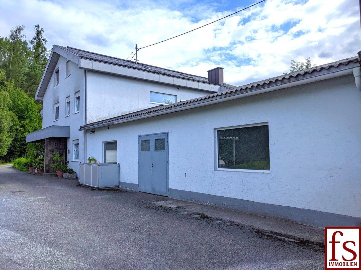 Seitenansicht des Hauses mit Garage und gepflastertem Vorplatz.