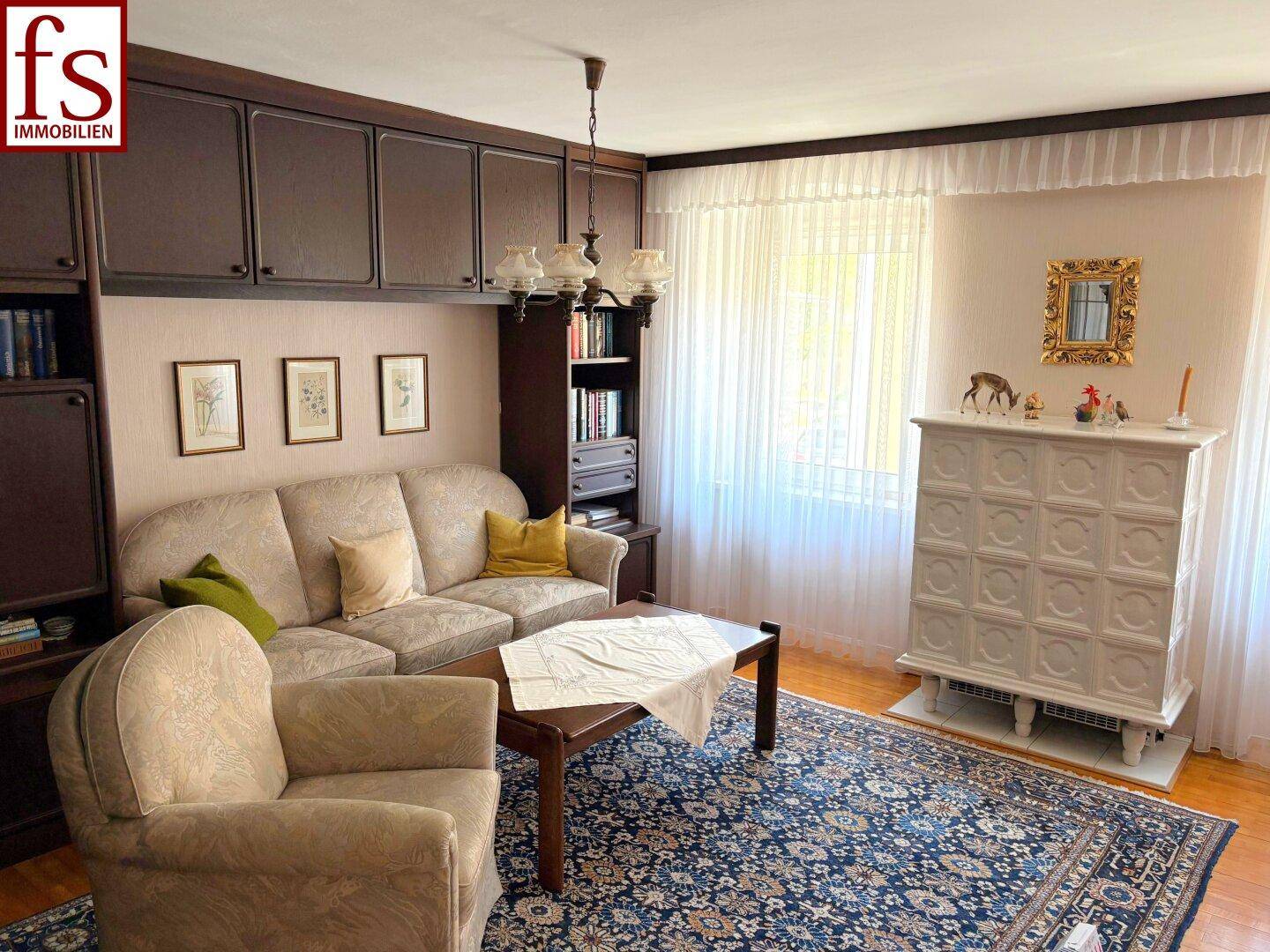 Wohnzimmer mit Kachelofen, Sofa und dunklen Einbauschränken, traditionell eingerichtet.
